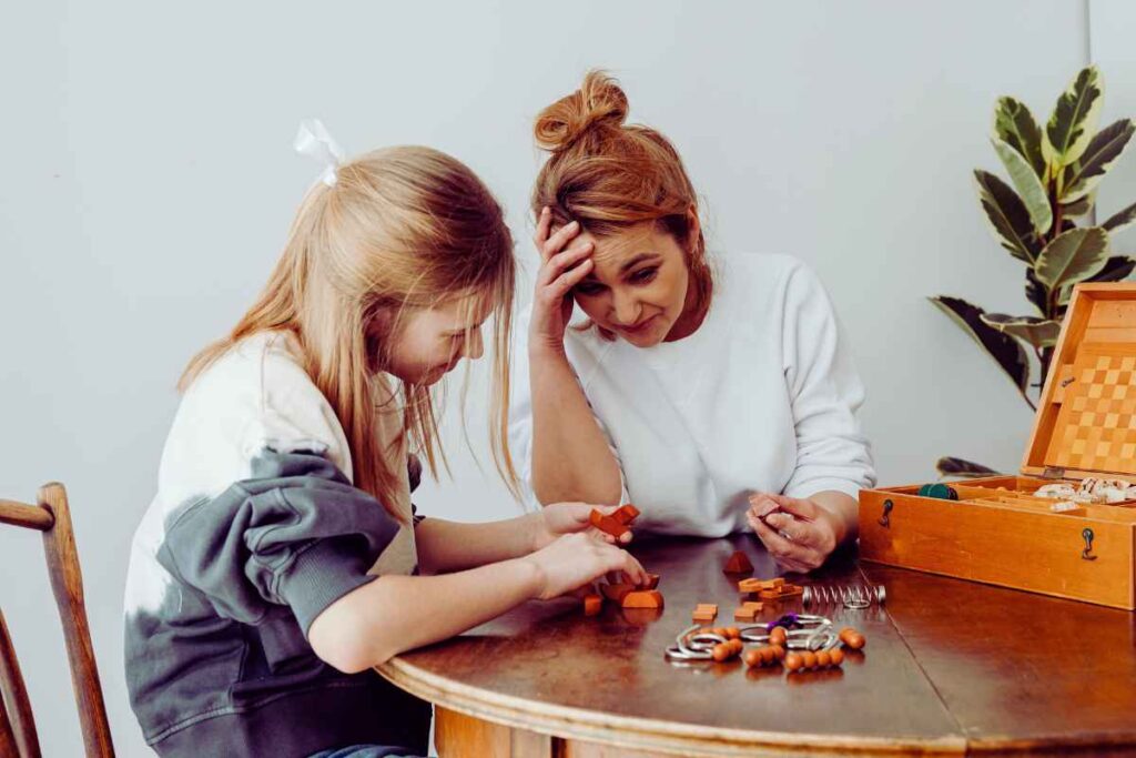 A mother and daughter sit at a table working on a puzzle, expressing teamwork and calm connection while managing frustration constructively.